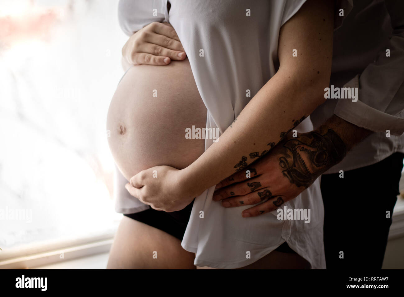 Dad's fingertips touch her belly, thinking about the life growing within. Stock Photo