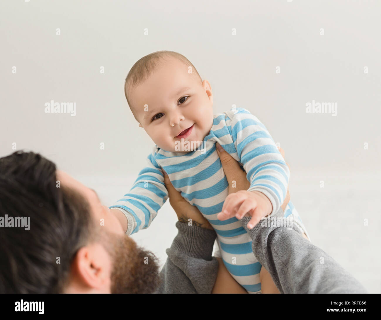 Dad holding happy baby son up in the air Stock Photo