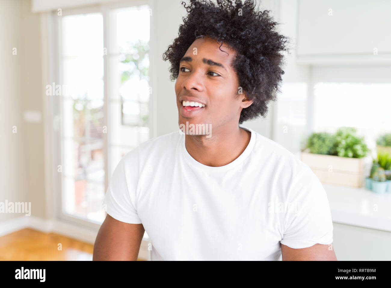 African American man wearing white t-shirt smiling looking side and ...