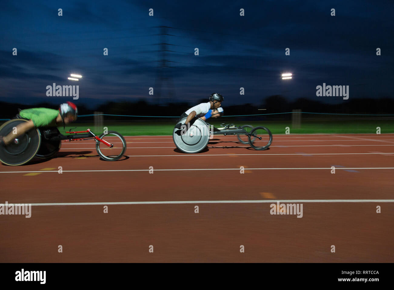 Paraplegic athletes speeding along sports track in wheelchair race Stock Photo