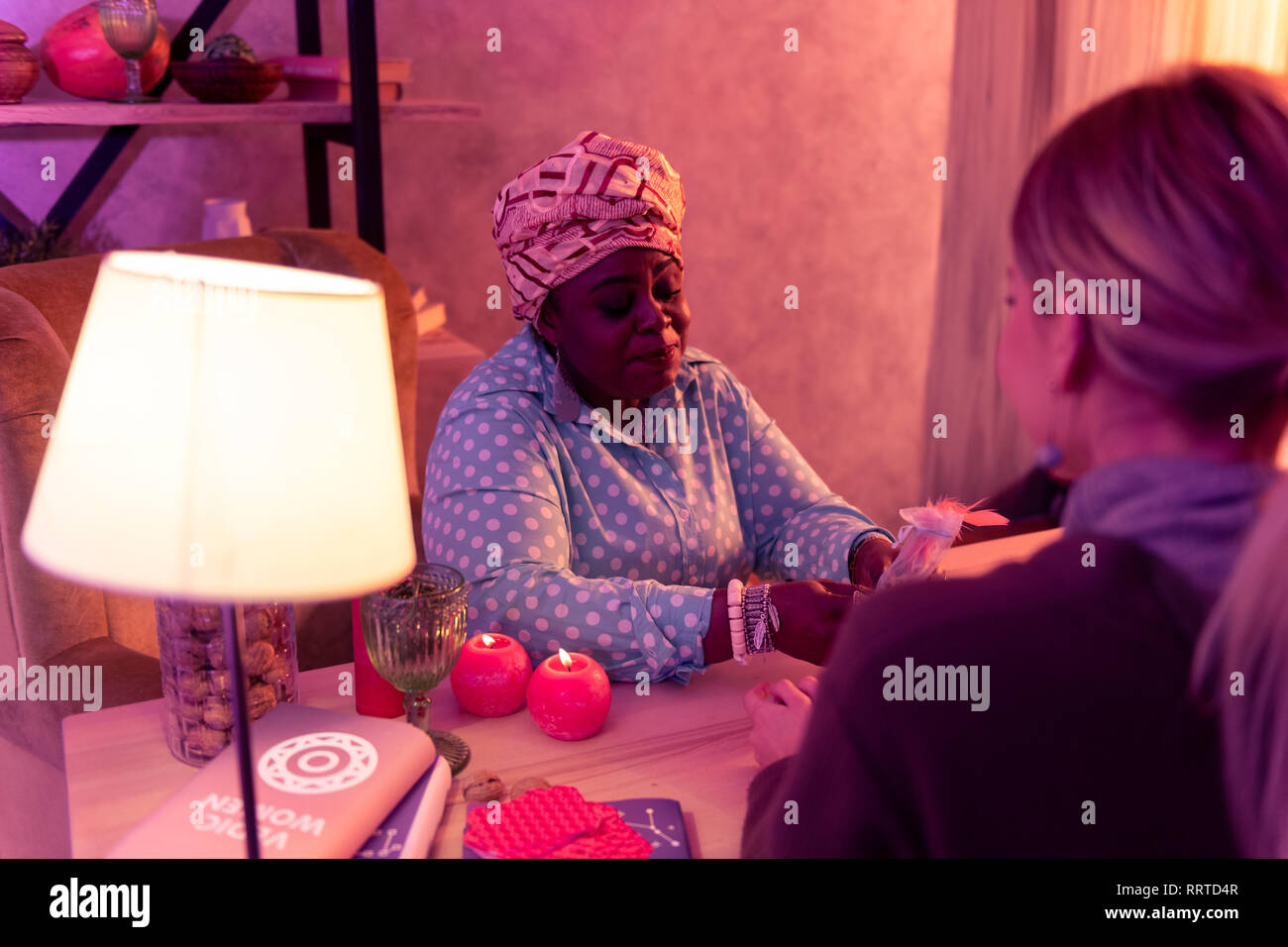 African american plump fortune-teller in ethnic headwear holding witchery accessory Stock Photo