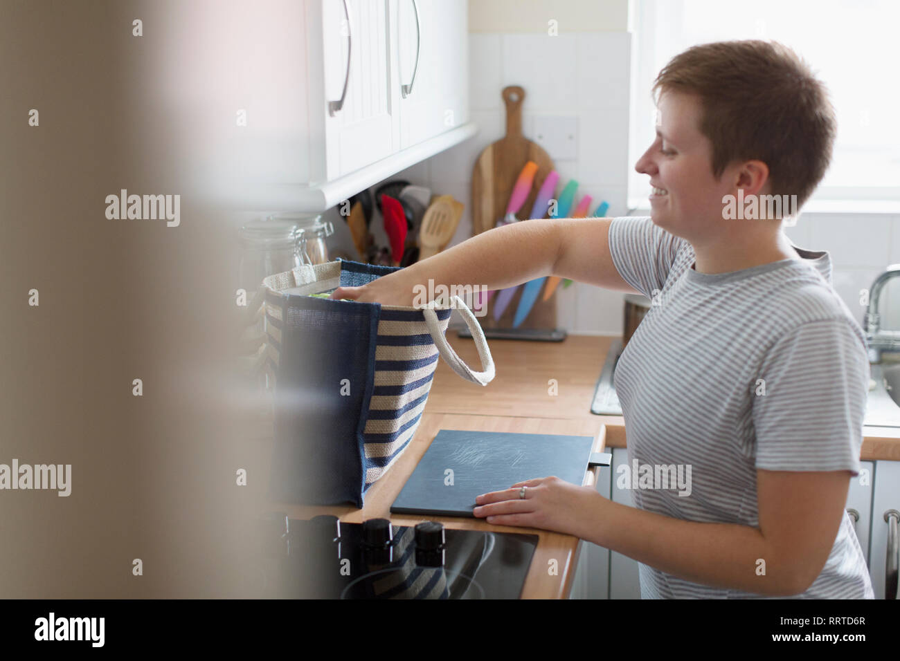 Young woman unpacking groceries in apartment kitchen Stock Photo
