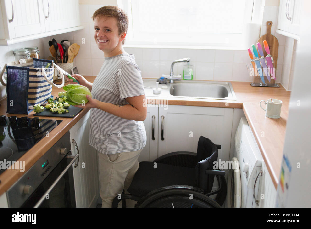 Portrait confident young woman with wheelchair cooking in apartment kitchen Stock Photo