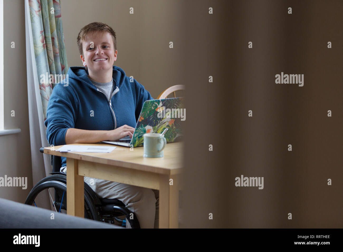 Portrait smiling, confident young woman in wheelchair at laptop Stock Photo
