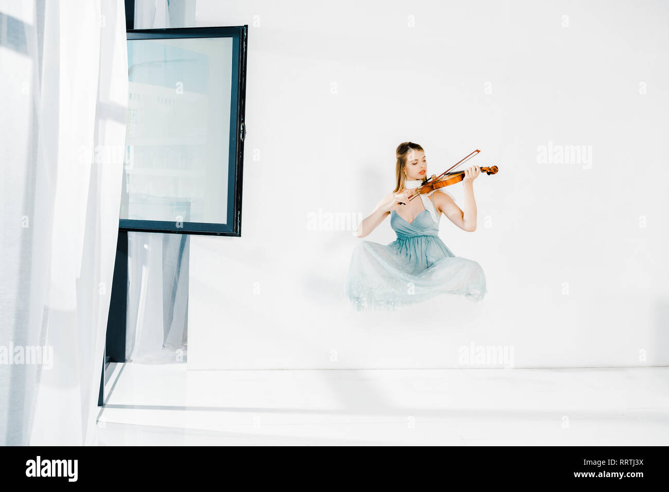 floating girl in blue dess playing violin on white background Stock ...