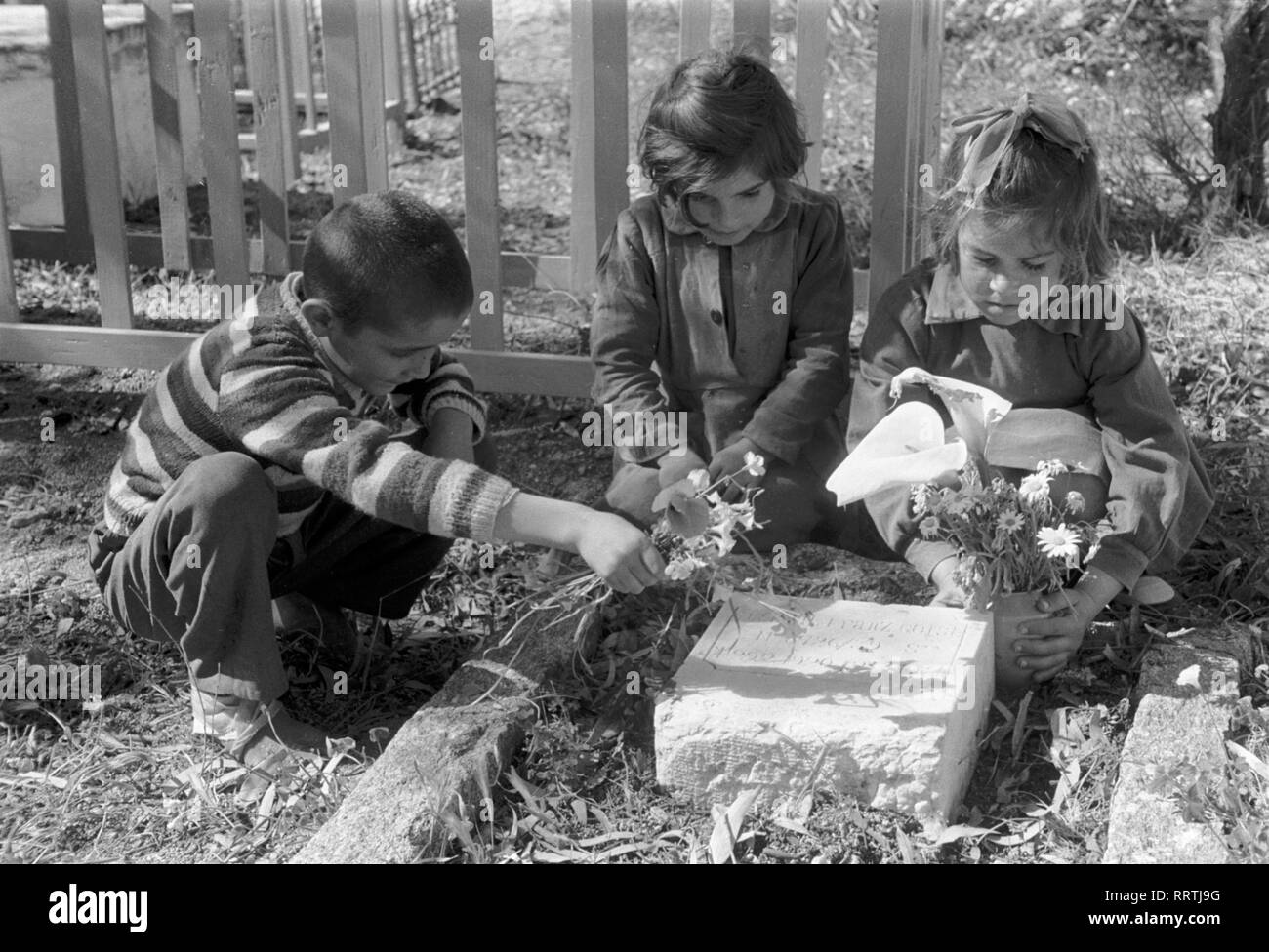 Travel to Greece - Greece, Mykonos island  - children sitting around a grave. Kinder beim Grab auf einem Friedhof auf der Insel Mykonos, Griechenland. Image date circa 1954. Photo Erich Andres Stock Photo