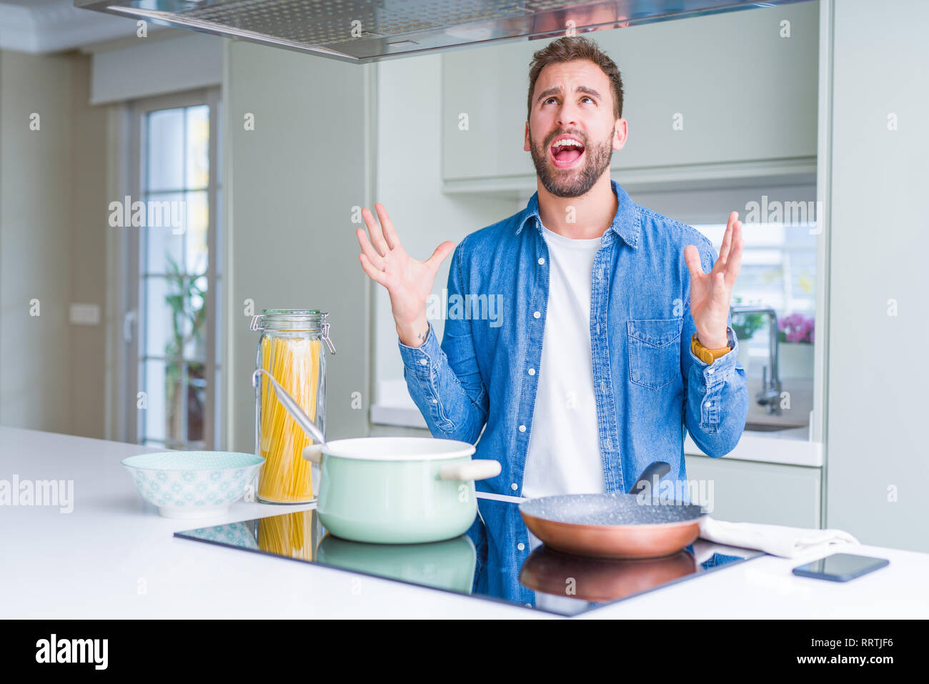 Handsome man cooking italian spaghetti pasta at the kitchen crazy and ...