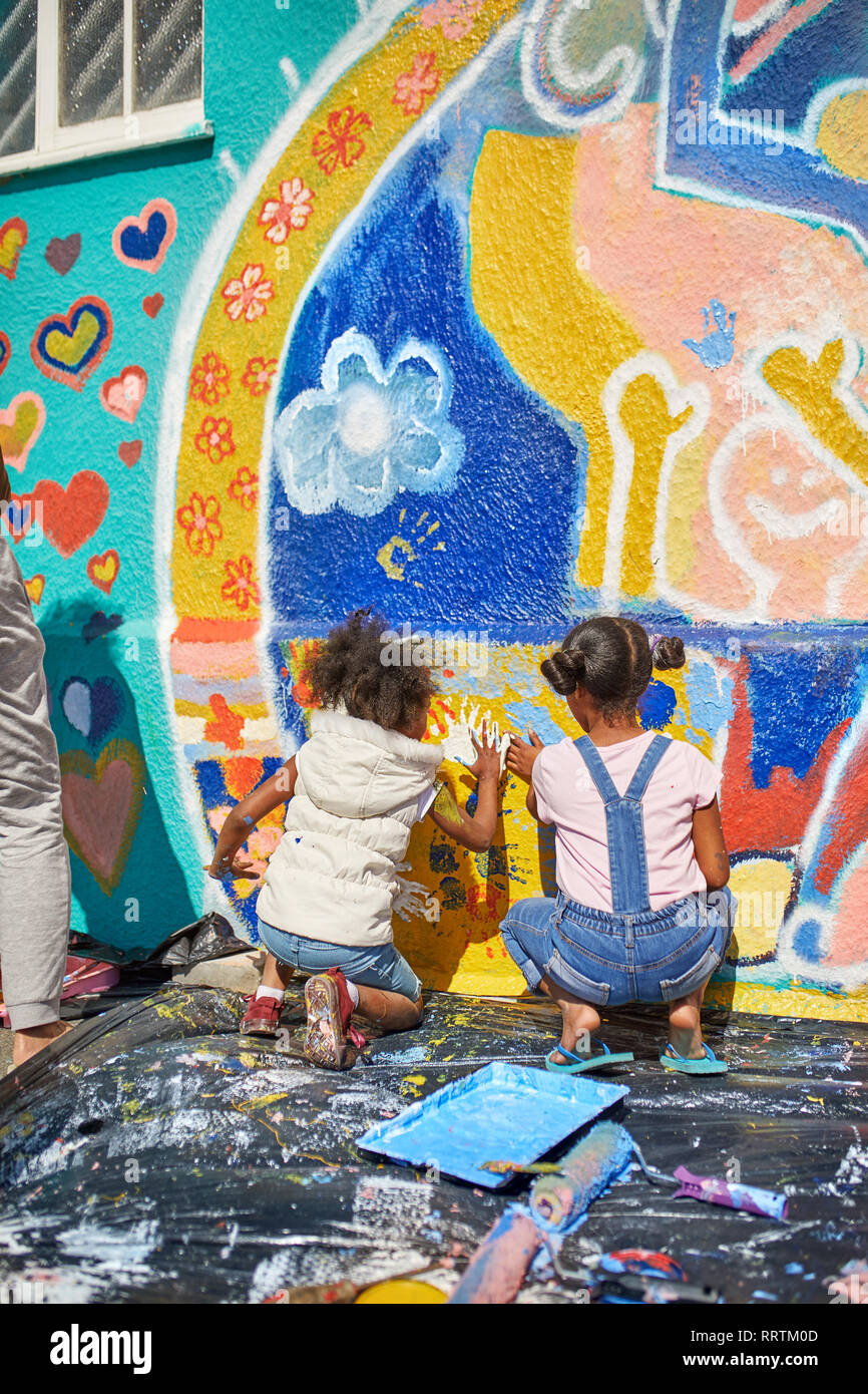 Girls painting vibrant mural on sunny wall Stock Photo