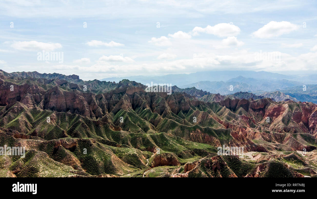 Aerial View of Binggou Danxia Canyon Landform in Zhangye, Sunan Region, Gansu Province, China. Sharp Pointy Peaks in the Geopark. Low Clouds and Blue  Stock Photo