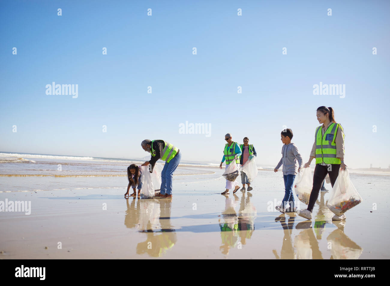 Volunteers cleaning litter from wet sand beach Stock Photo