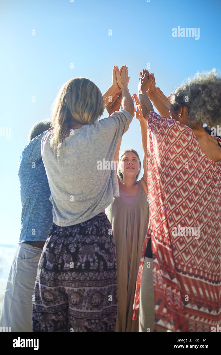 Group standing in circle with arms raised during yoga retreat Stock Photo