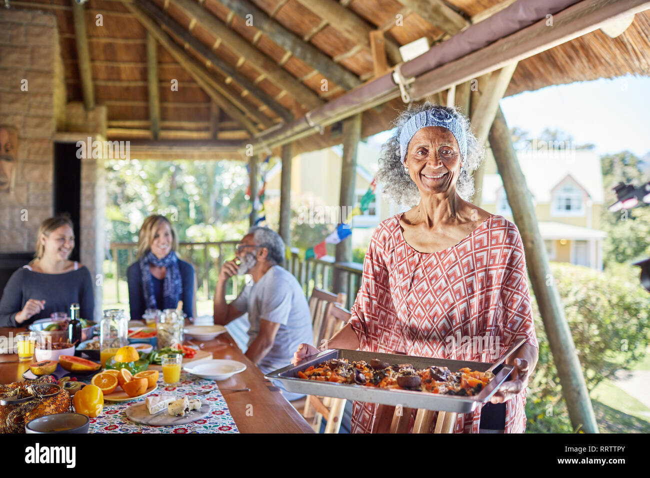 Portrait smiling senior woman serving food to guests in hut Stock Photo