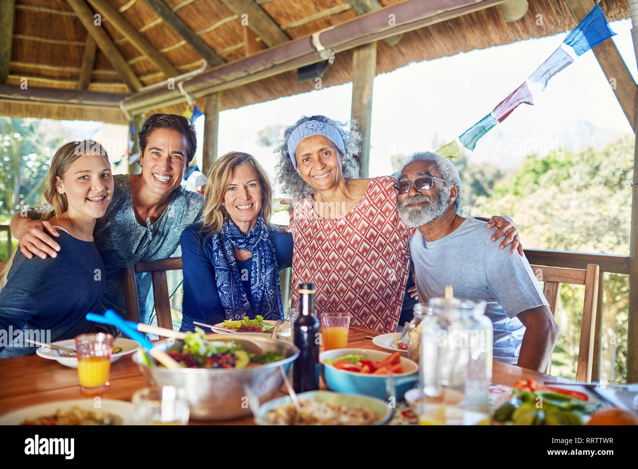 Portrait happy friends enjoying healthy meal in hut during yoga retreat Stock Photo