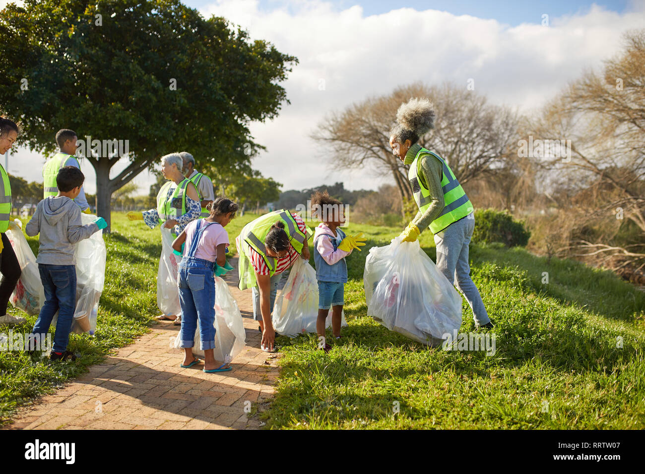 Volunteers cleaning up litter in sunny park Stock Photo