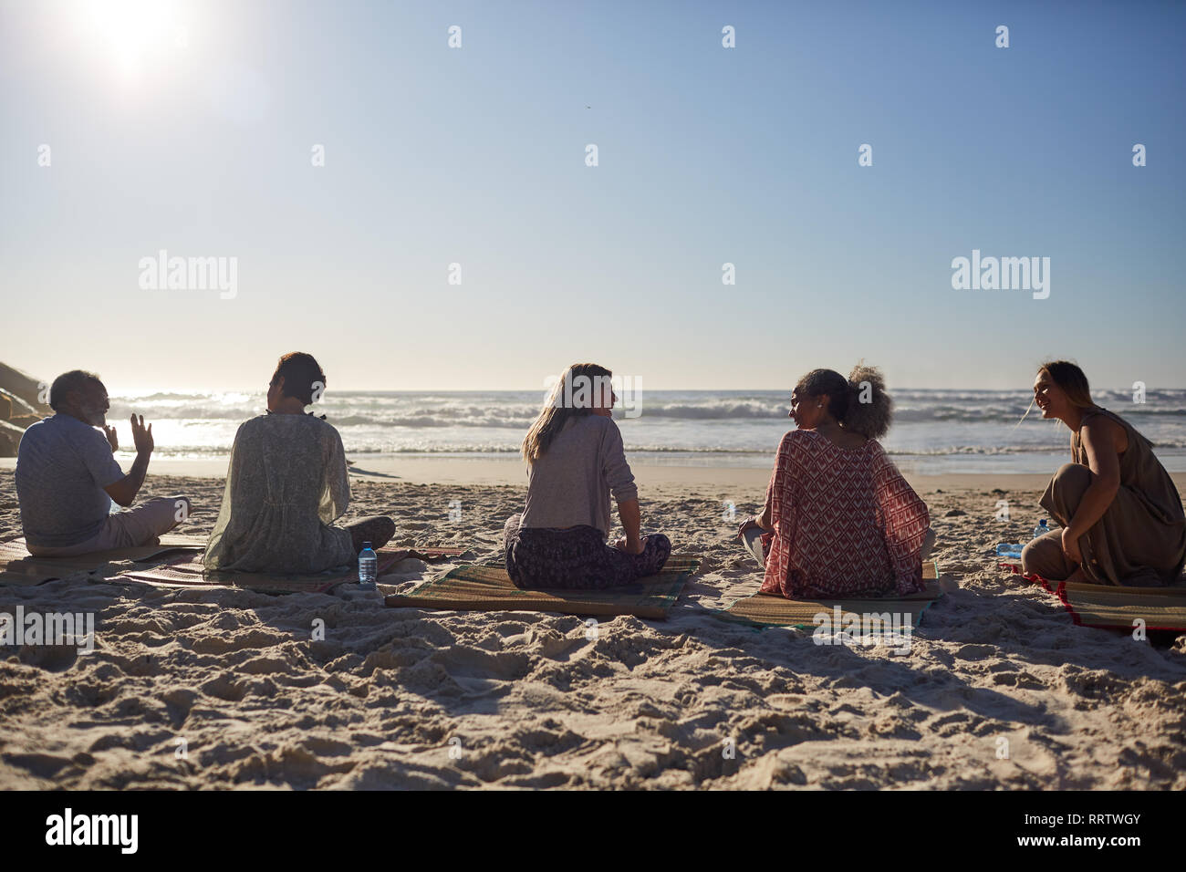 Yoga class talking on sunny beach during yoga retreat Stock Photo