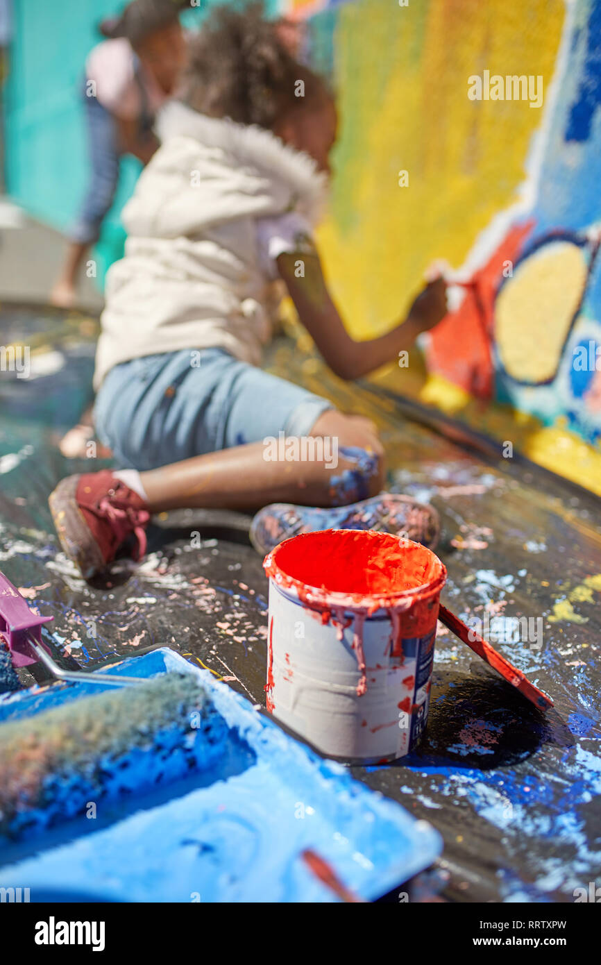 Girl painting mural behind paint can Stock Photo