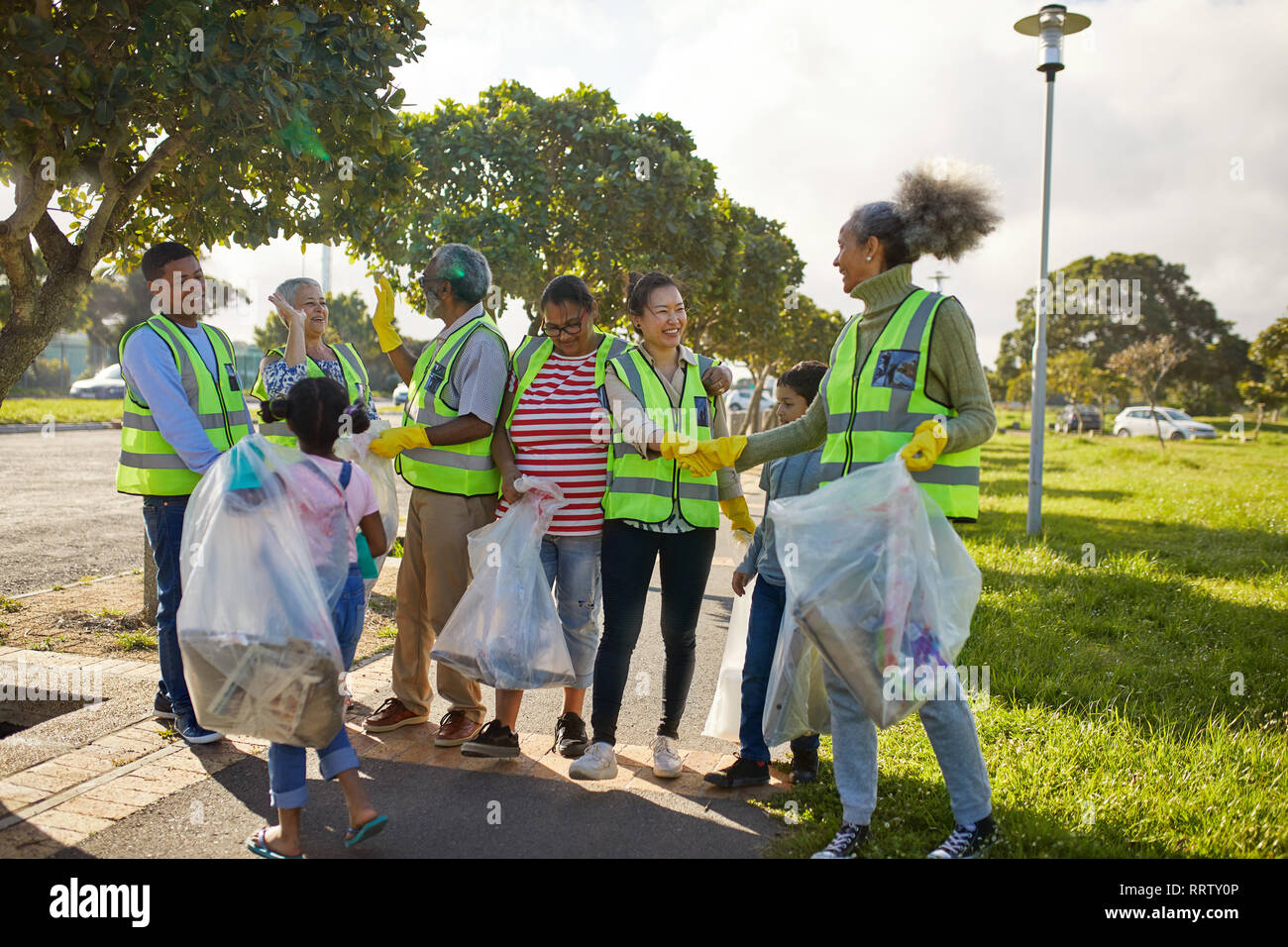 Happy volunteers celebrating, cleaning litter from sunny park Stock Photo