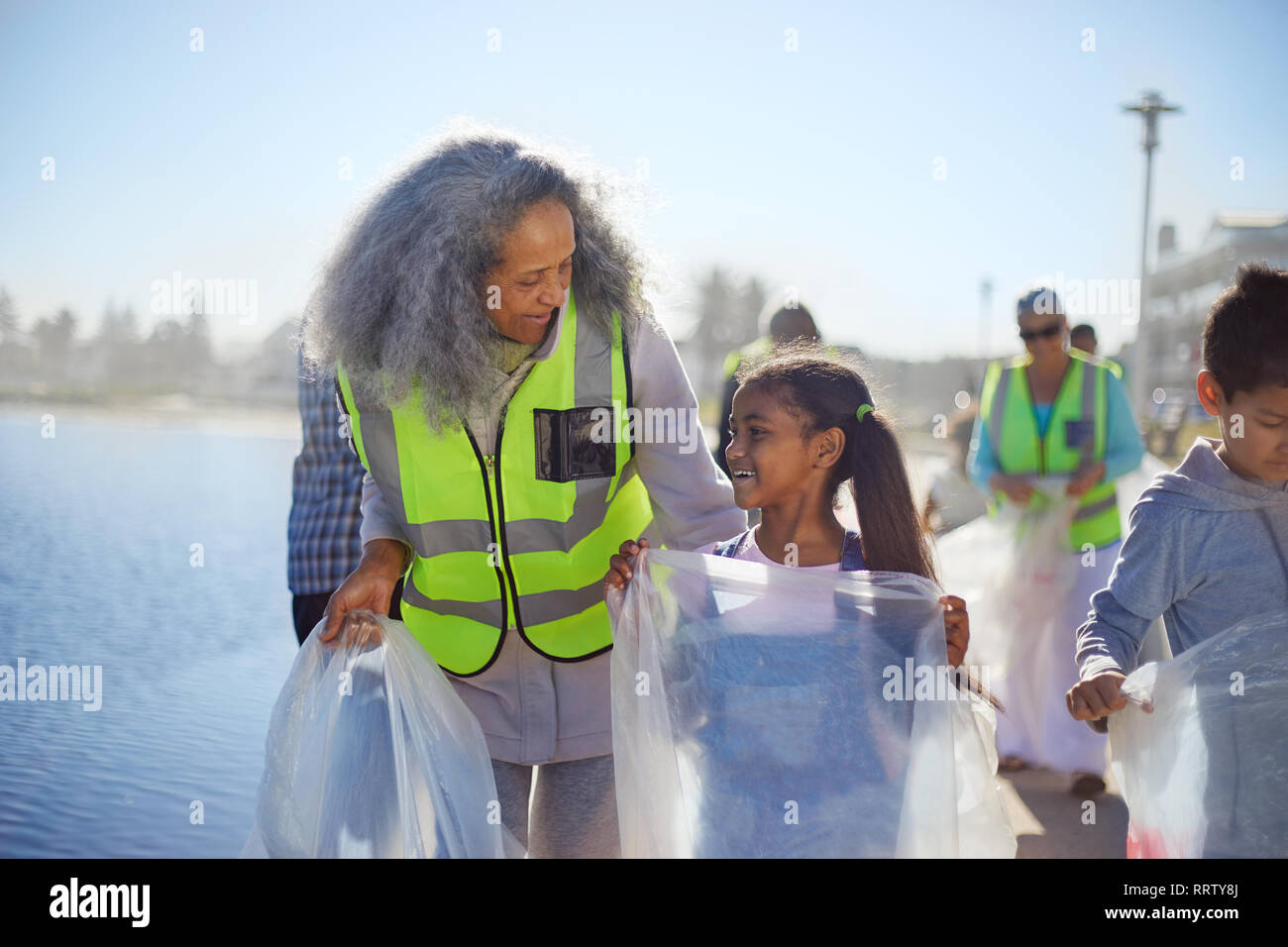 Grandmother and granddaughter volunteers picking up litter on boardwalk Stock Photo