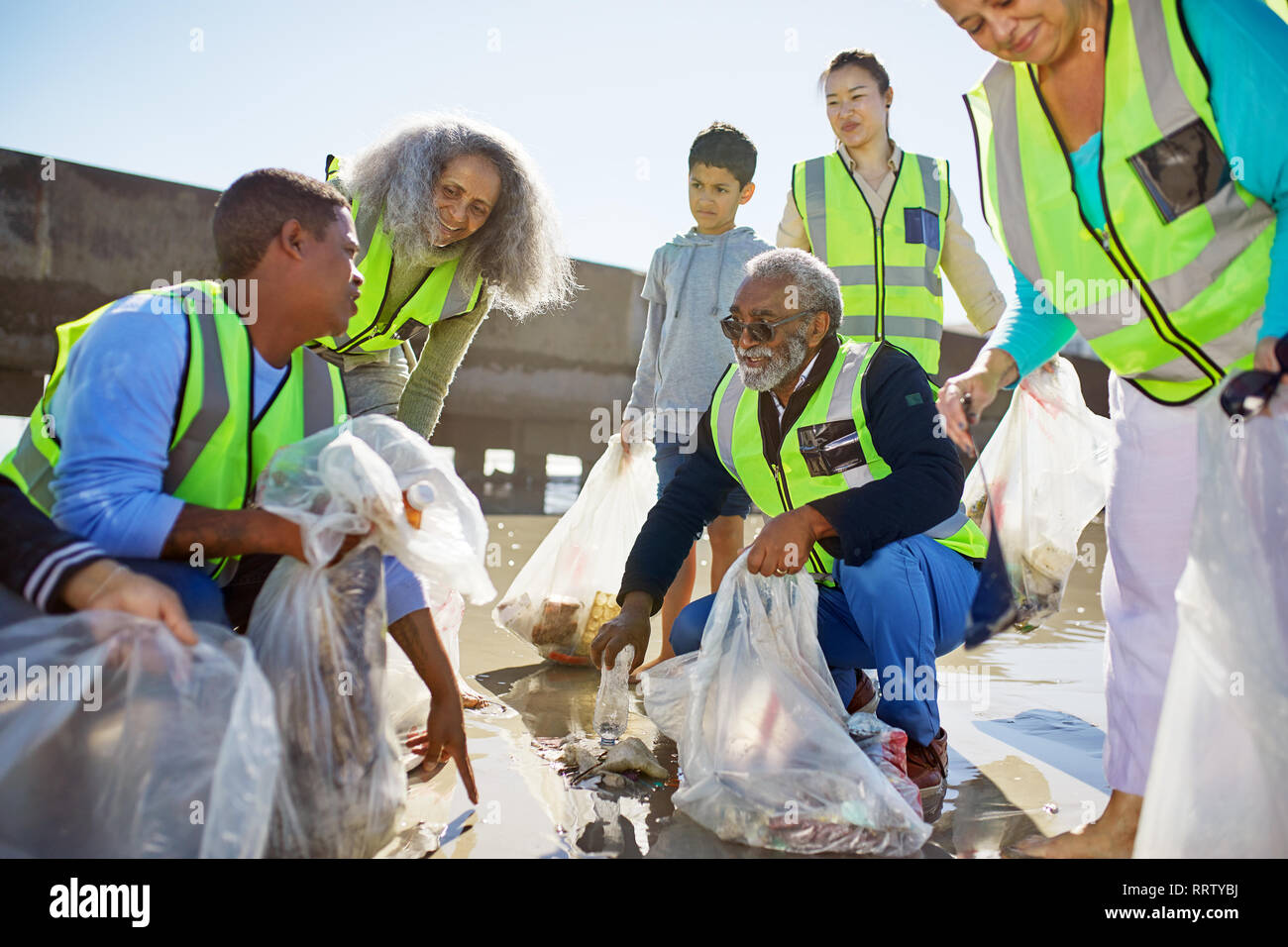 Volunteers cleaning up litter on sunny beach Stock Photo