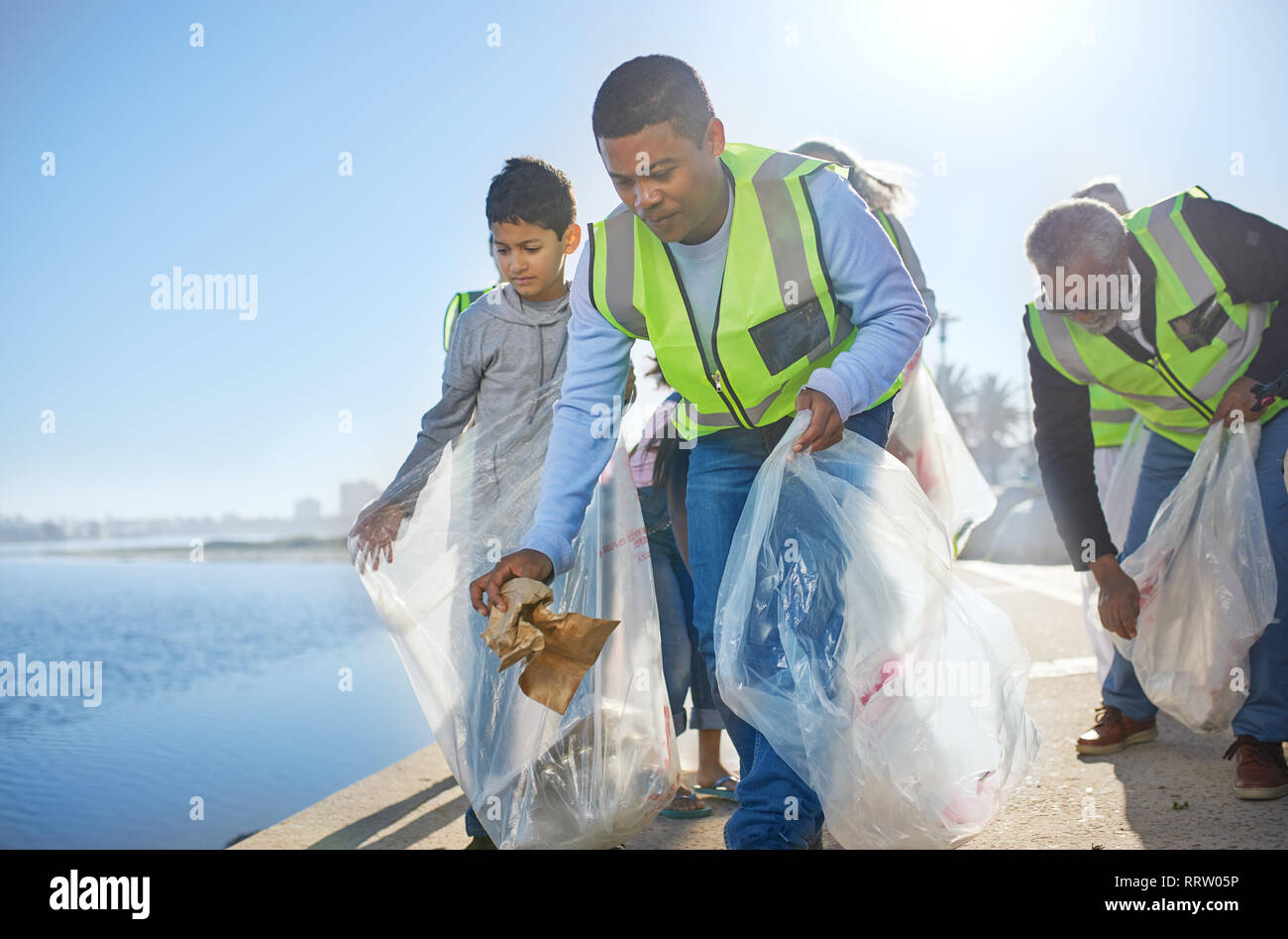 Multi-generation family men volunteering, picking up litter on waterfront pier Stock Photo