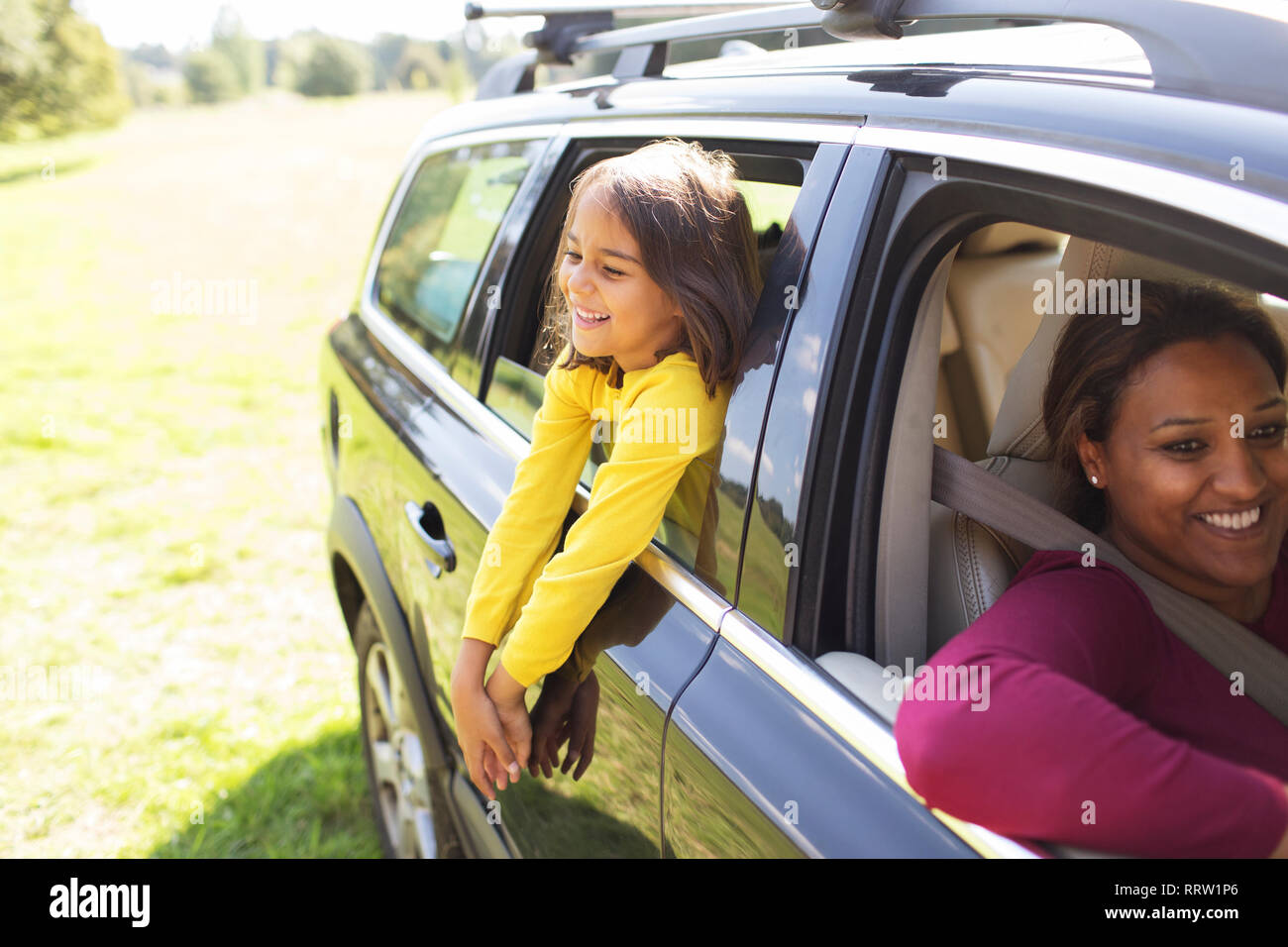 Carefree girl leaning out window of car Stock Photo