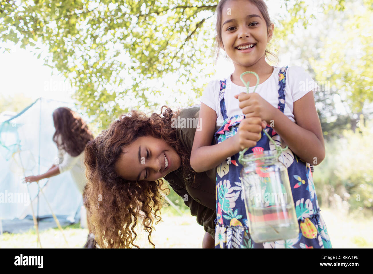 Portrait happy sisters catching fish in jar Stock Photo