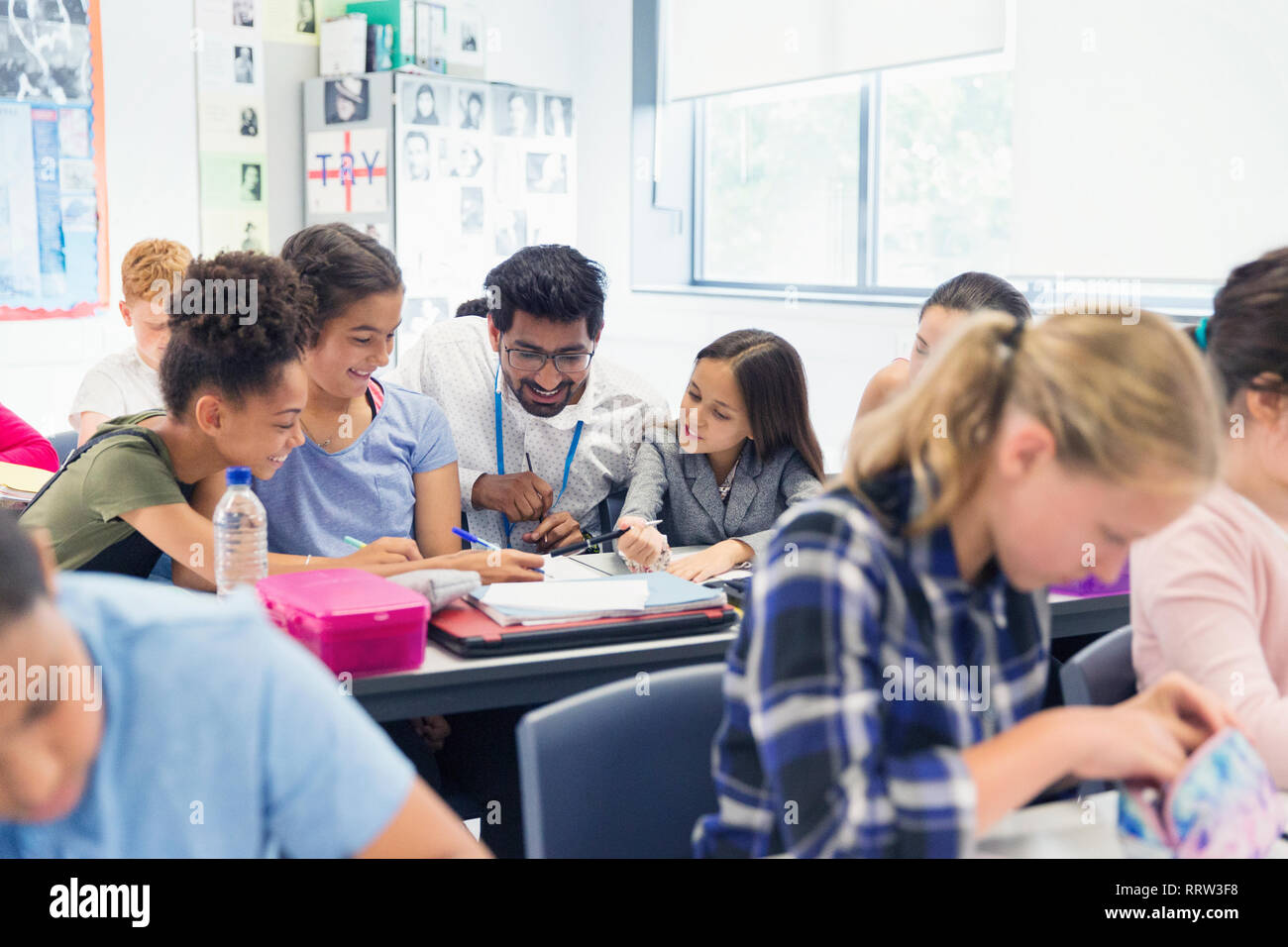 Teacher helping junior high school students at desk in classroom Stock Photo