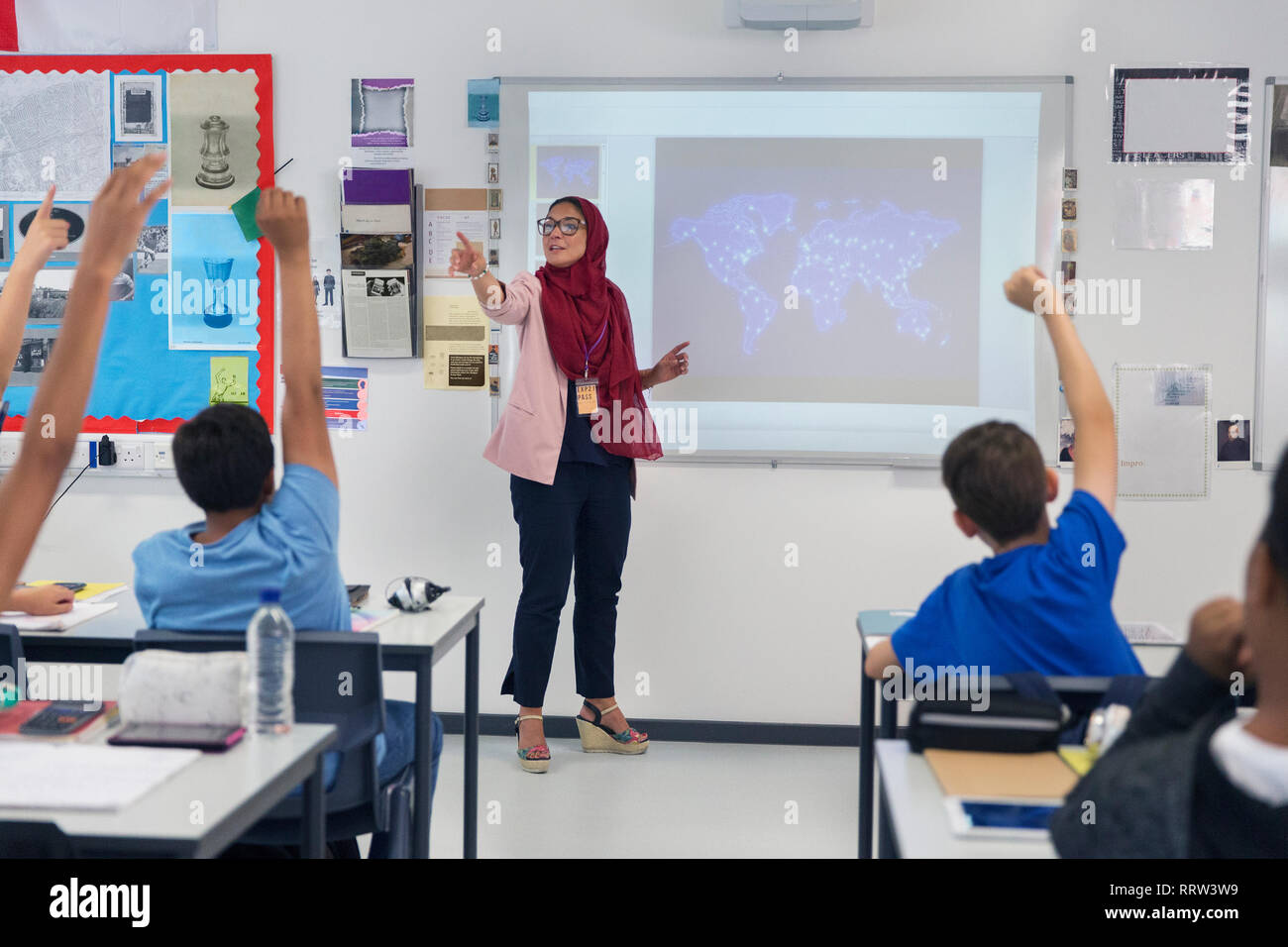 Female teacher in hijab leading lesson, calling on students in classroom Stock Photo