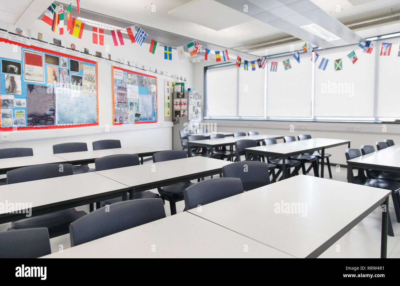 International flags hanging over desks in classroom Stock Photo