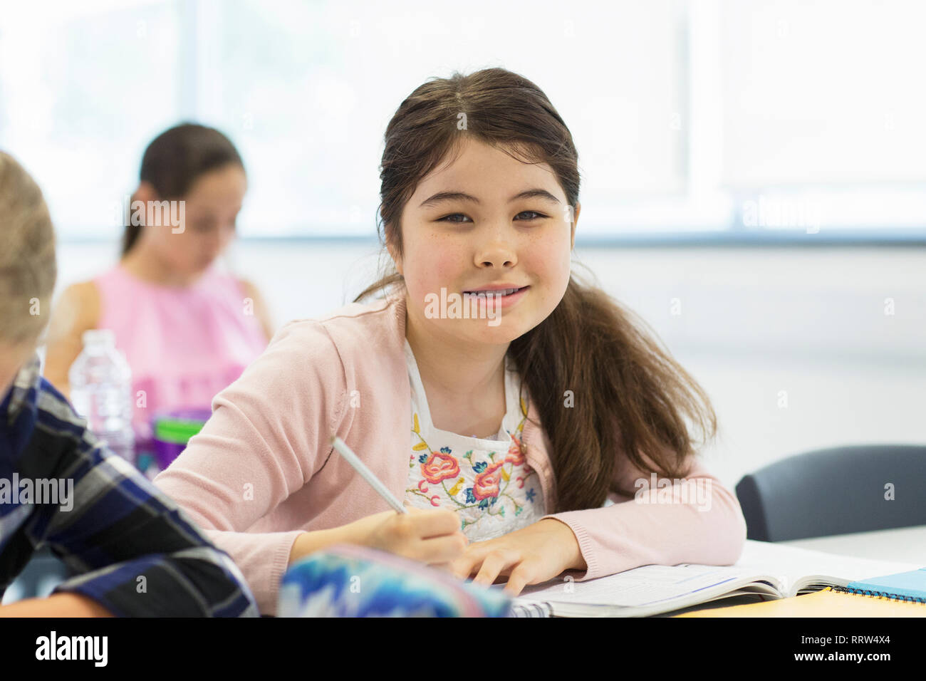 Portrait confident junior high school girl student doing homework in classroom Stock Photo