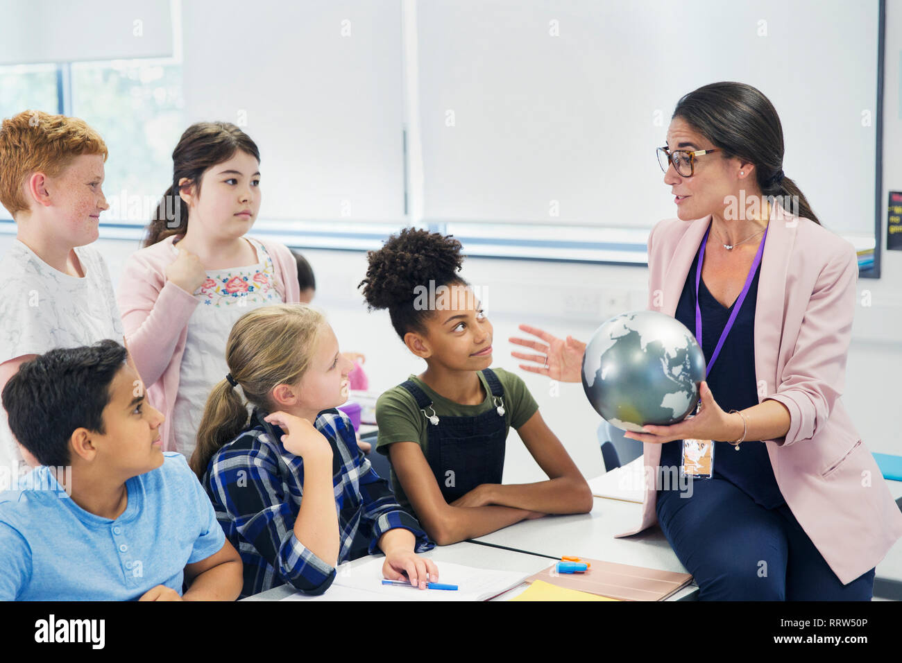 Attentive junior high school students watching geography teacher with globe Stock Photo