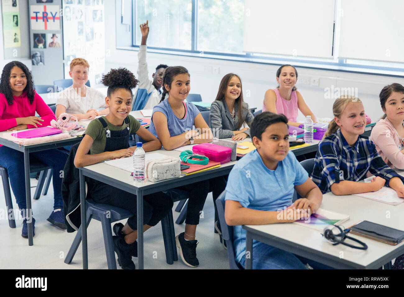 Junior high school students enjoying lesson at desks in classroom Stock Photo