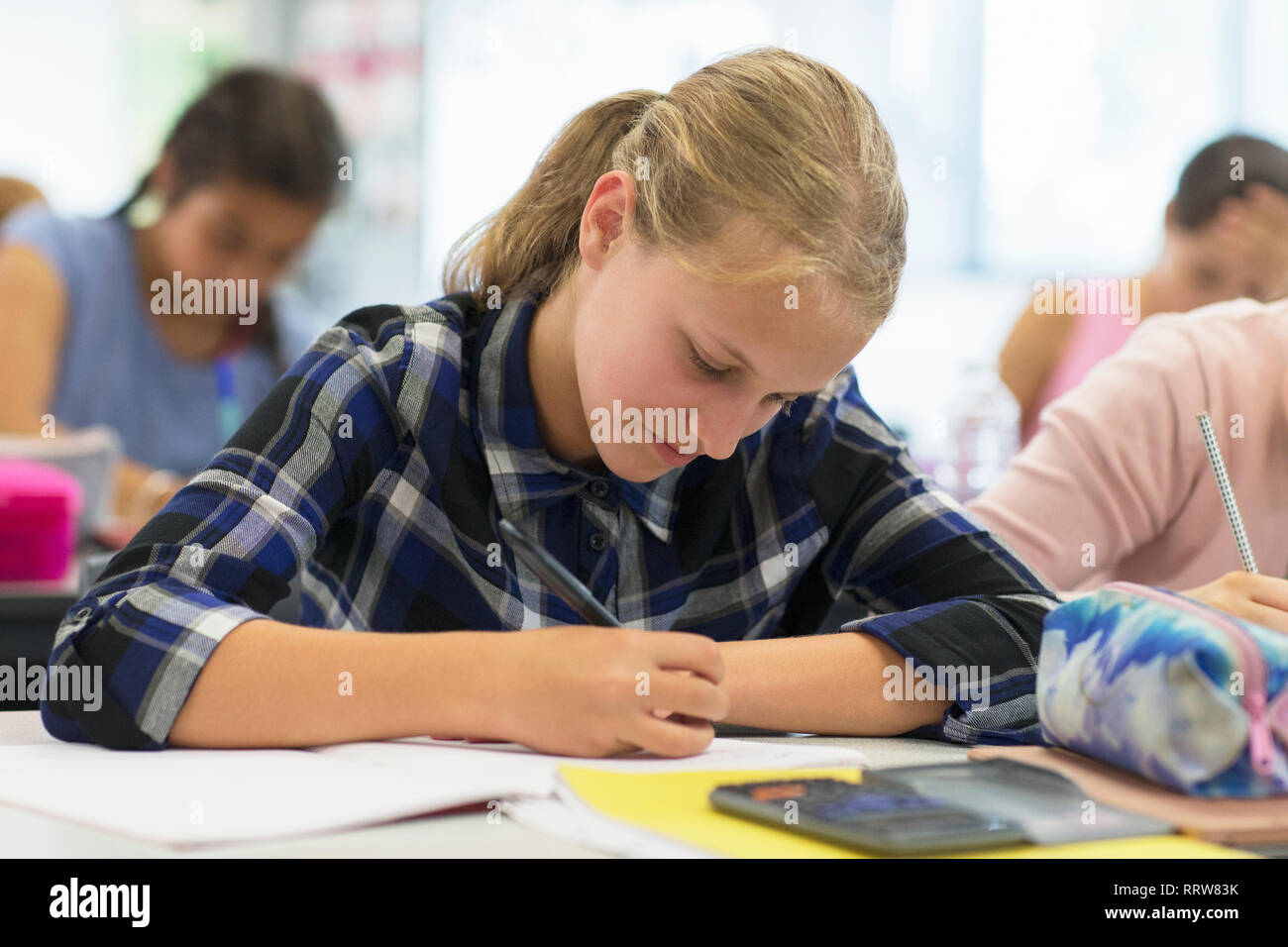 Focused junior high school student doing homework in classroom Stock Photo