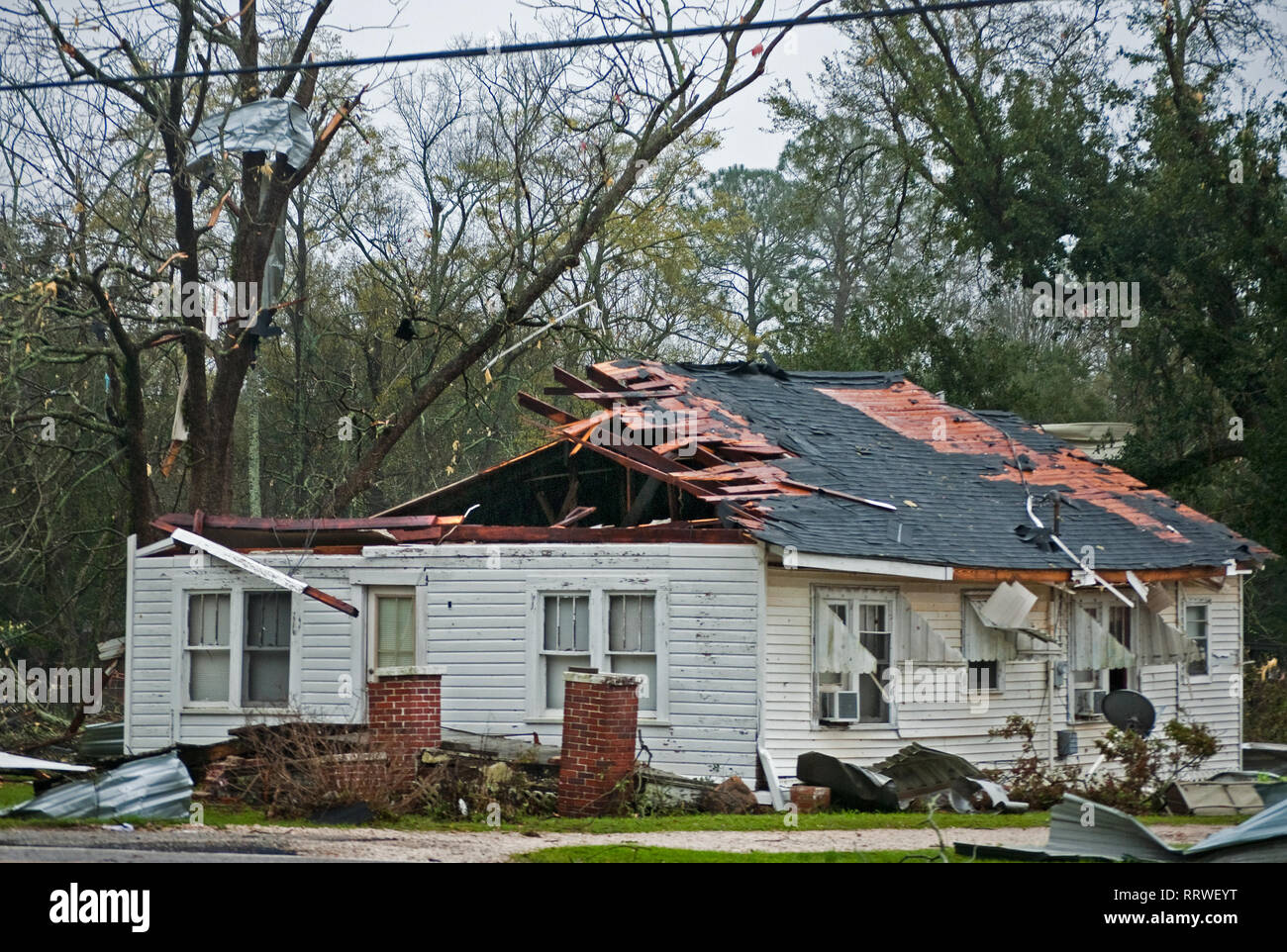 A roof is torn away and debris litters the trees following an EF-2  tornado, March 9, 2011, in Theodore, Alabama. Stock Photo