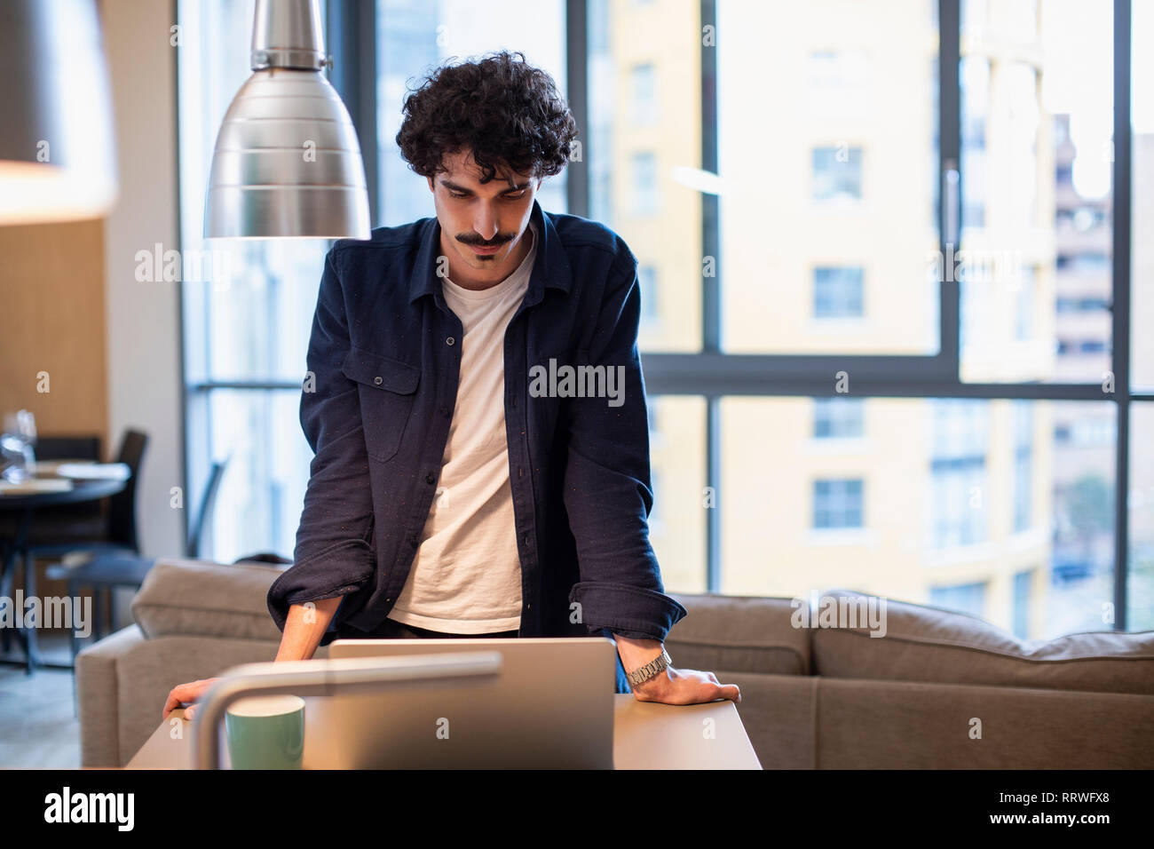 Man using laptop in urban apartment kitchen Stock Photo