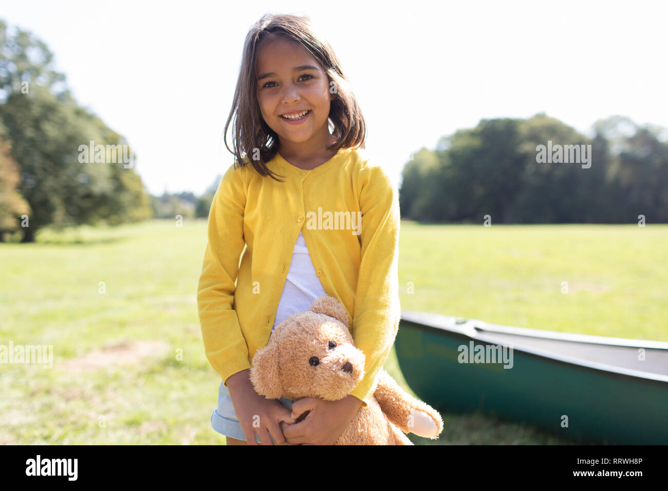 Portrait smiling, cute girl with teddy bear in sunny field Stock Photo ...