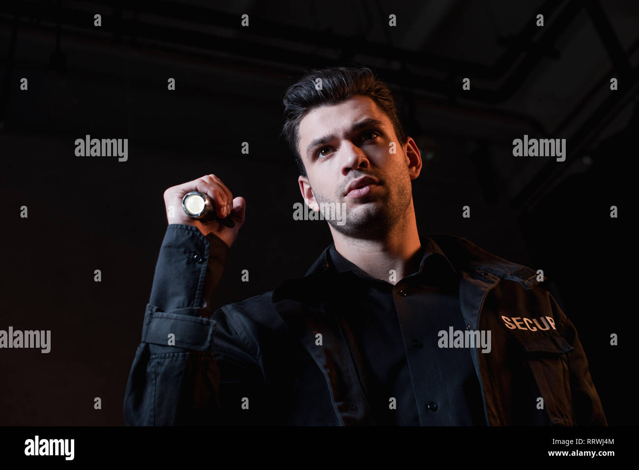 handsome guard in black uniform holding flashlight Stock Photo