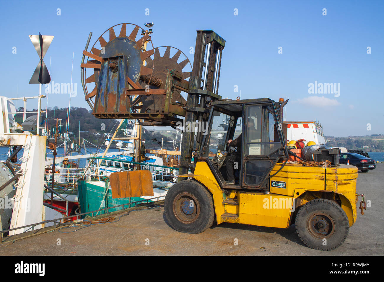 forklift truck lifting equipment onto a fishing trawler. Stock Photo