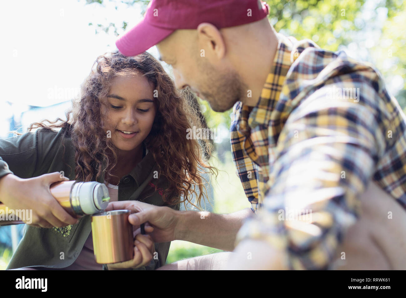 Daughter pouring coffee from insulated drink container for father Stock Photo