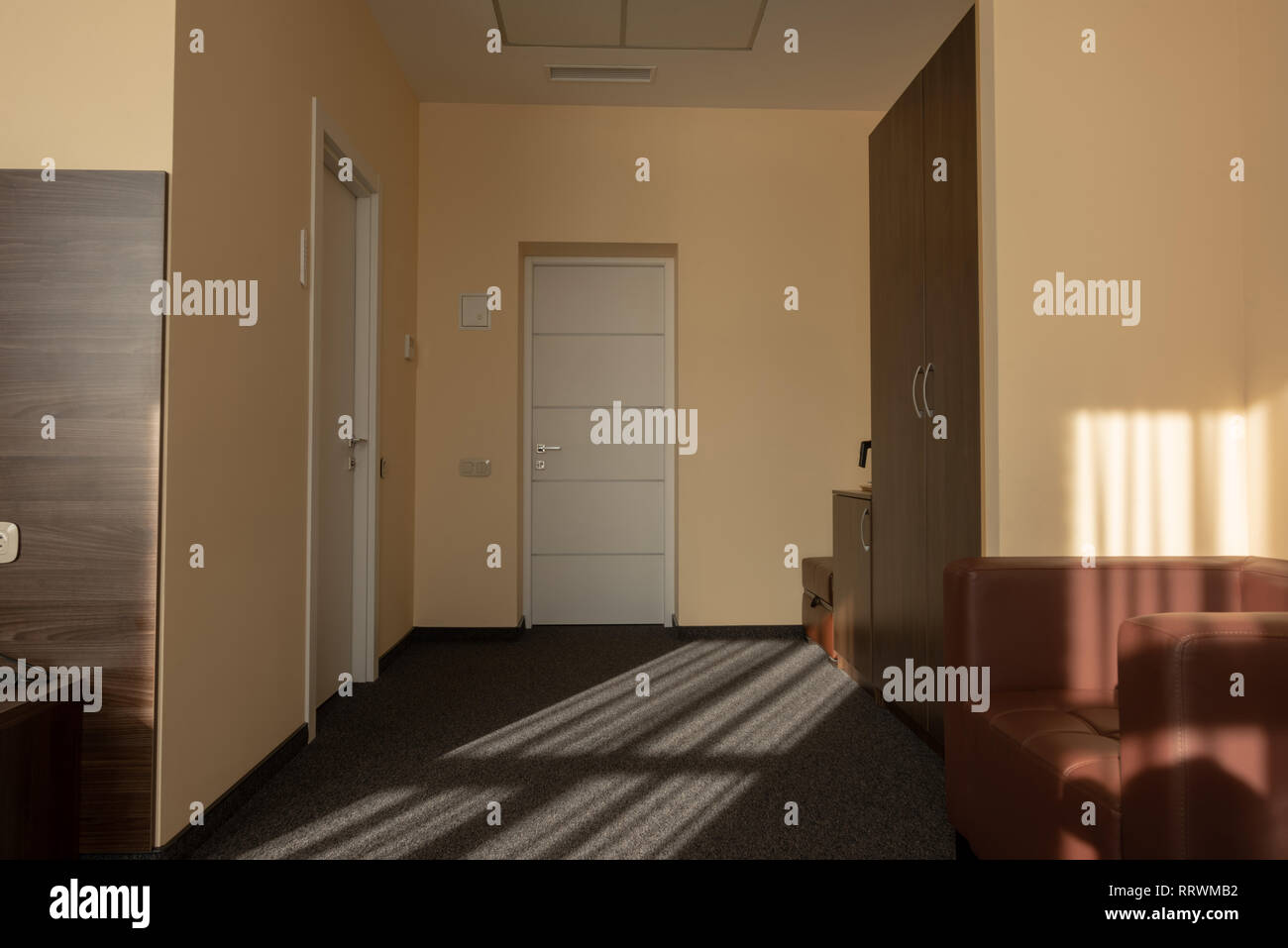 beige hotel room interior with wardrobe, armchair and doors Stock Photo