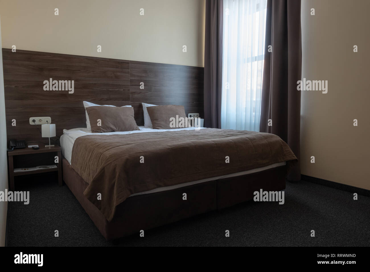 hotel room interior with window and brown bed Stock Photo