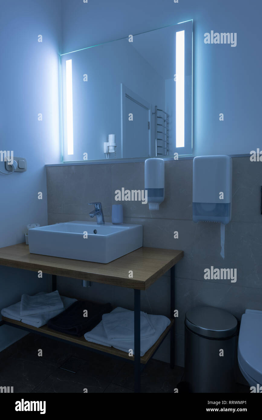 hotel bathroom with washstand and towels with neon light on mirror Stock Photo
