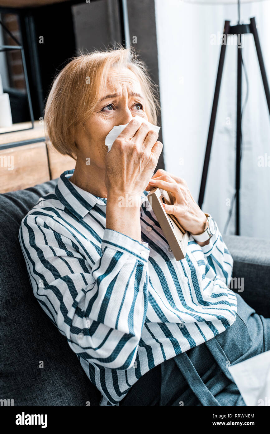 sad senior woman wiping face from tears with tissue and crying while