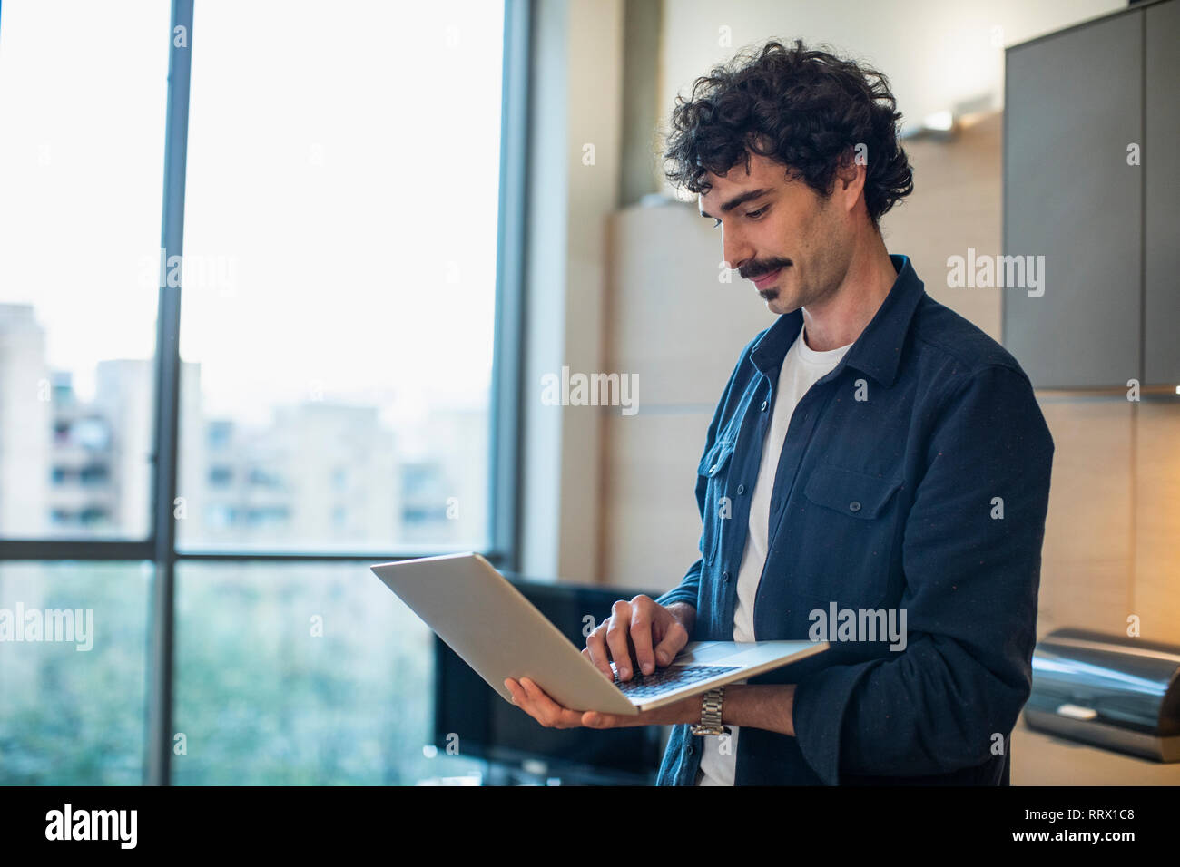 Man using laptop in apartment Stock Photo