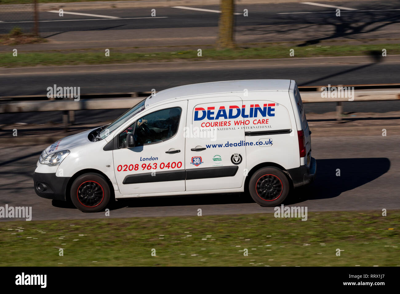 Deadline couriers who care, white van driving on the road. Mail, parcel courier business Stock Photo