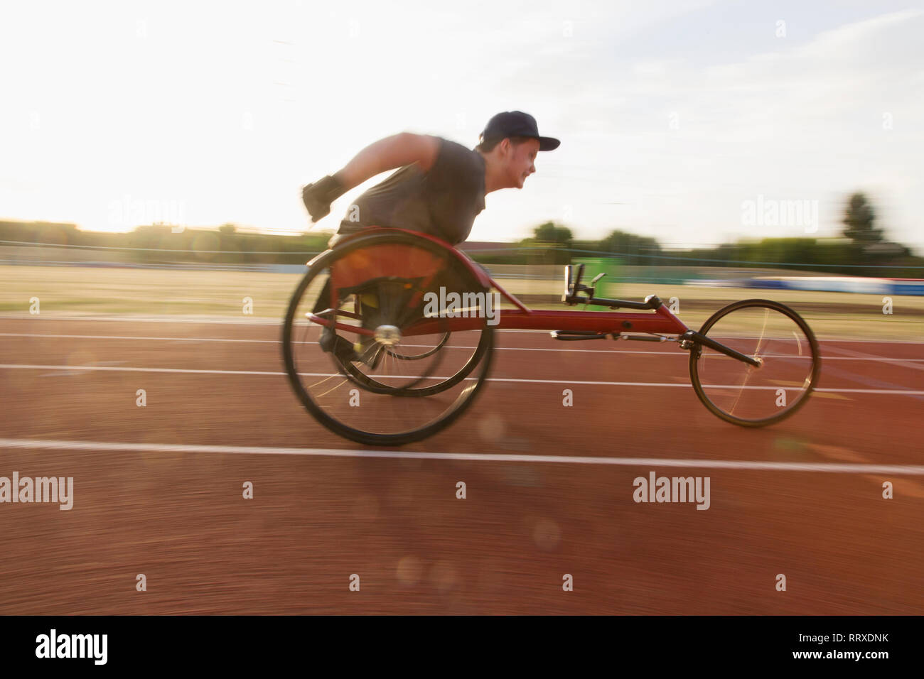 Teenage boy paraplegic athlete speeding along sports track in wheelchair race Stock Photo