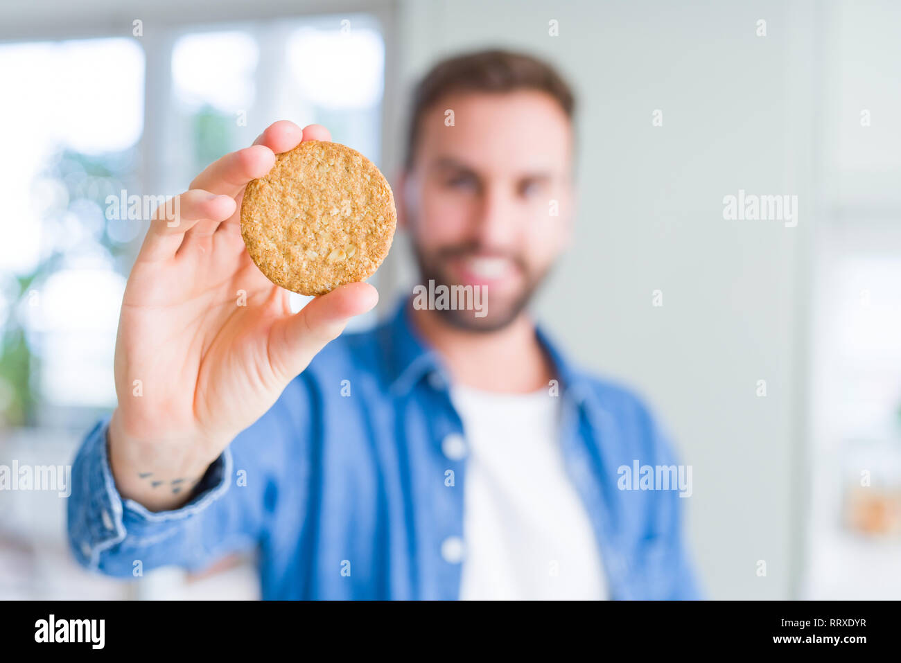 Handsome man eating healthy whole grain biscuit with a happy face