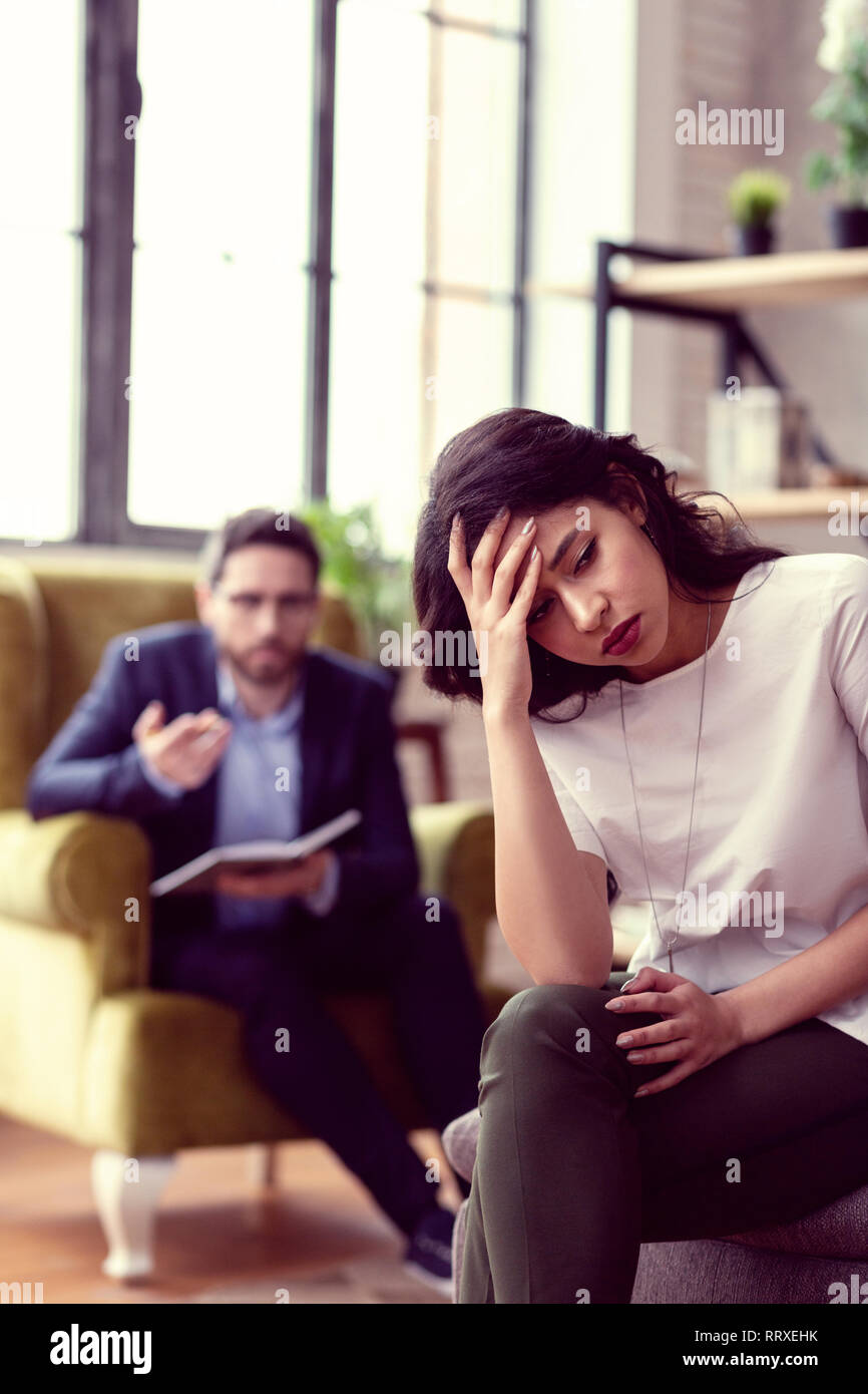 Cheerless upset young woman visiting a psychologist Stock Photo