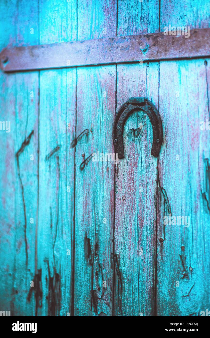 Old metal horseshoe hanging on blue wooden door Stock Photo