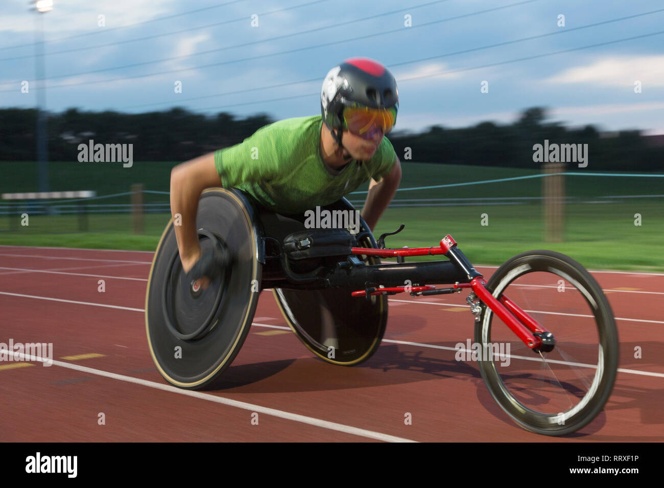 Determined young male paraplegic athlete speeding along sports track in ...